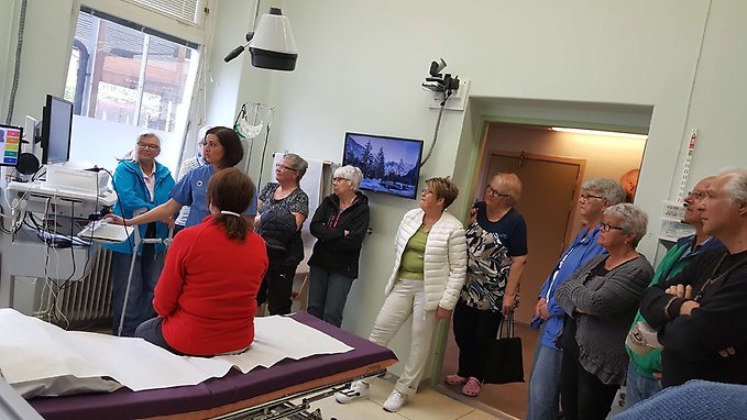 människor står upp i ett akutrum och tittar på en sjuksköterska som demonstrerar den nya tekniska utrustningen