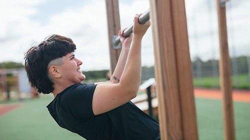  Person gör pull-ups på utegym.