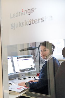 en person sitter med headset framför dubbla datorskärmar