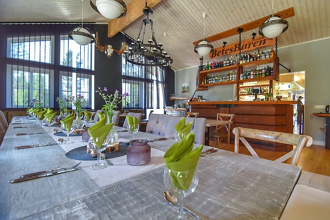 Bild inifrån Big River Camps restaurang och matsal, med ett dukat långbord och dekorativa trädetaljer och älghorn på väggarna.