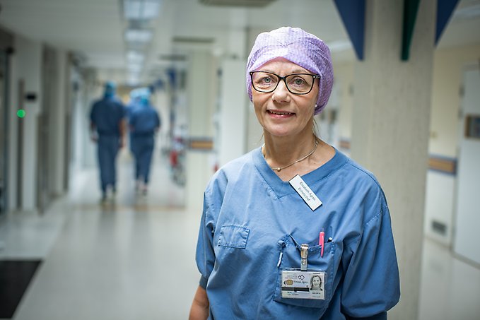 en kvinna klädd i operationskläder står i en sjukhuskorridor